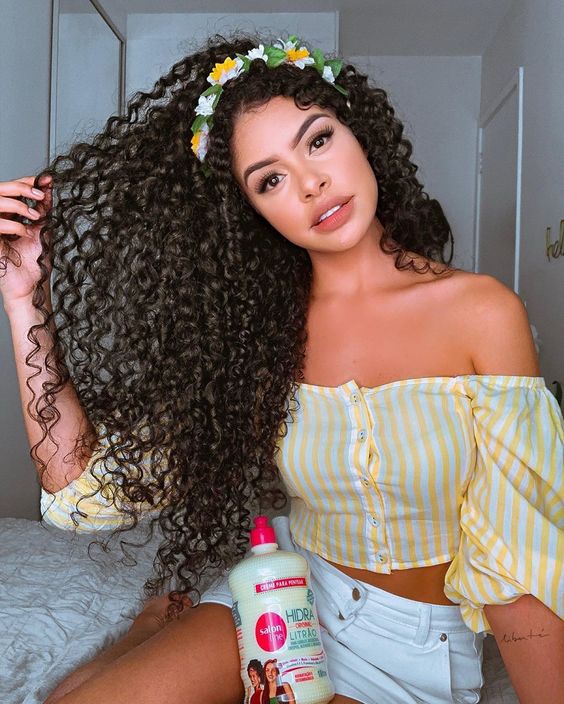 Imagem com cabelo cacheado com tiara de flores
