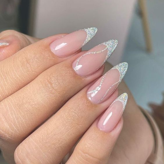 Imagem com unhas brancas com glitter com pontas finas e com detalhes em glitter