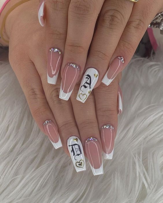 Imagem com unhas brancas com glitter, pedraria e lettering