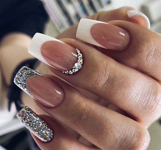 Imagem com unhas brancas com glitter, francesinha metálica e pedraria