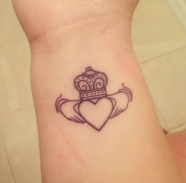 Imagem com tatuagem tribal feminina Claddagh de coroa no pulso