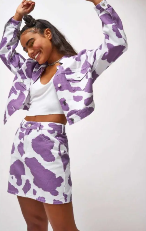 Imagem com jaqueta cropped e saia com estampa de vaca lilás