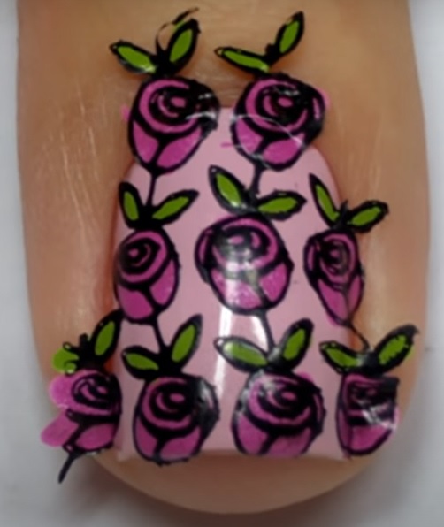 Imagem com unhas com esmalte rosa claro  com adesivo sendo aplicado