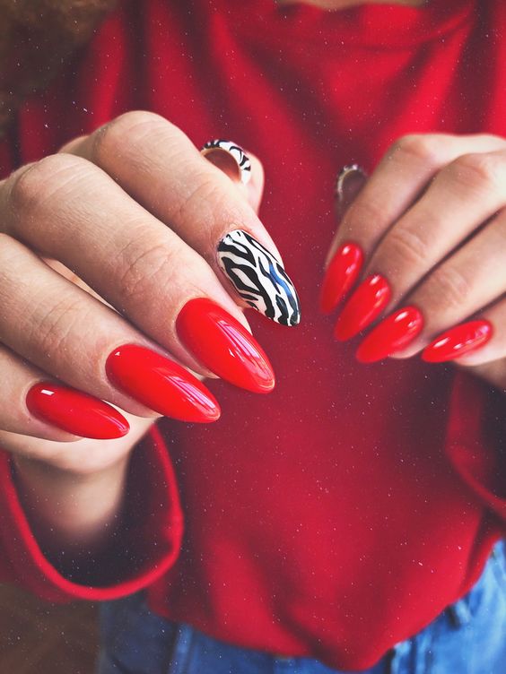 Imagem com Unhas almond decoradas com vermelho e estampa de zebra