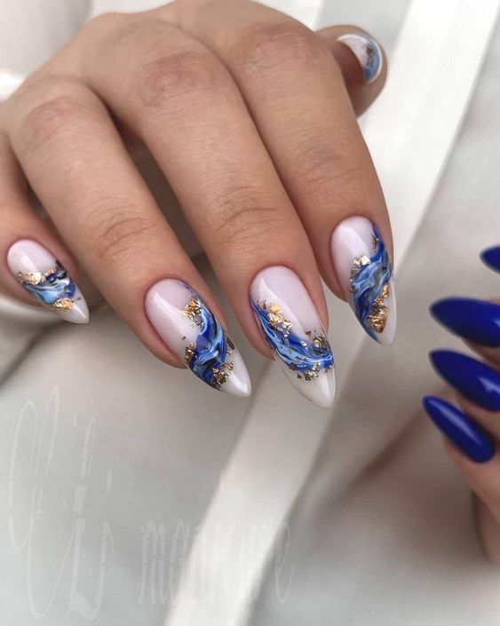 Imagem com Unhas almond decoradas com detalhes marmorizados azuis e dourados