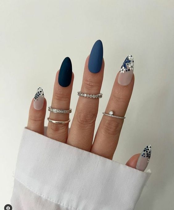 Imagem com Unhas almond decoradas com tons de azul e flores brancas e azuis