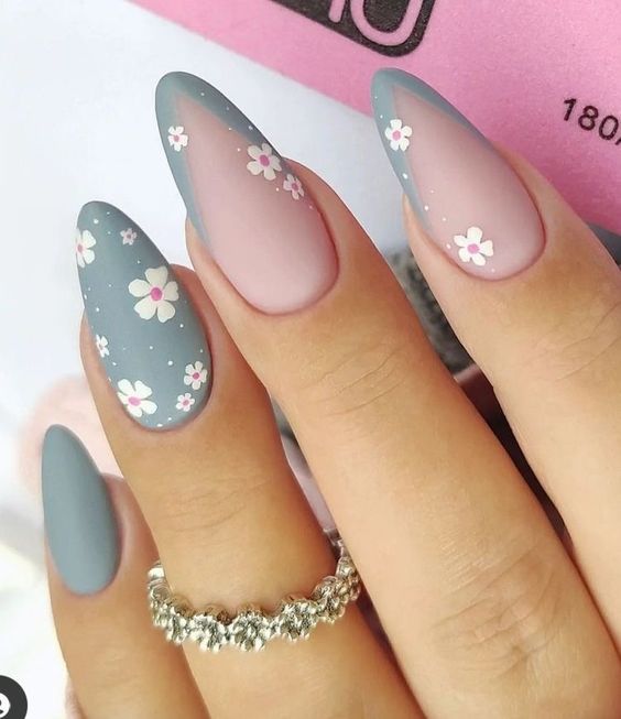 Imagem com Unhas almond decoradas com azul claro, nude e flores brancas delicadas