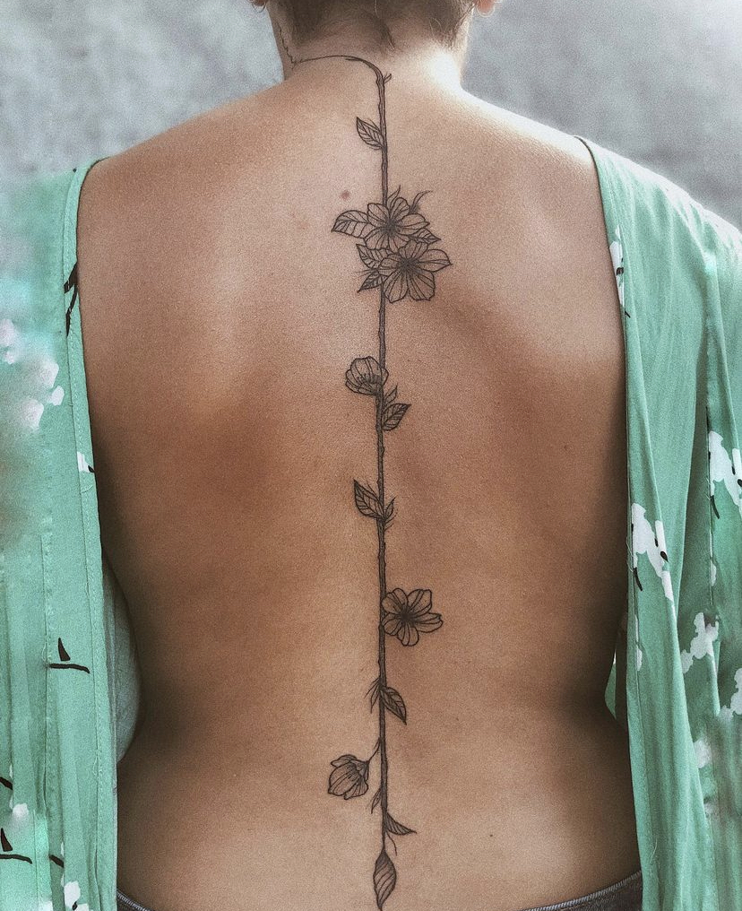 Imagem com tatuagem de flor nas costas: flores em ramo central