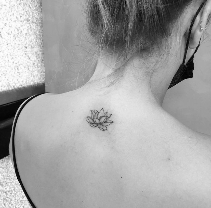 Imagem com tatuagem de flor nas costas: lótus pequena