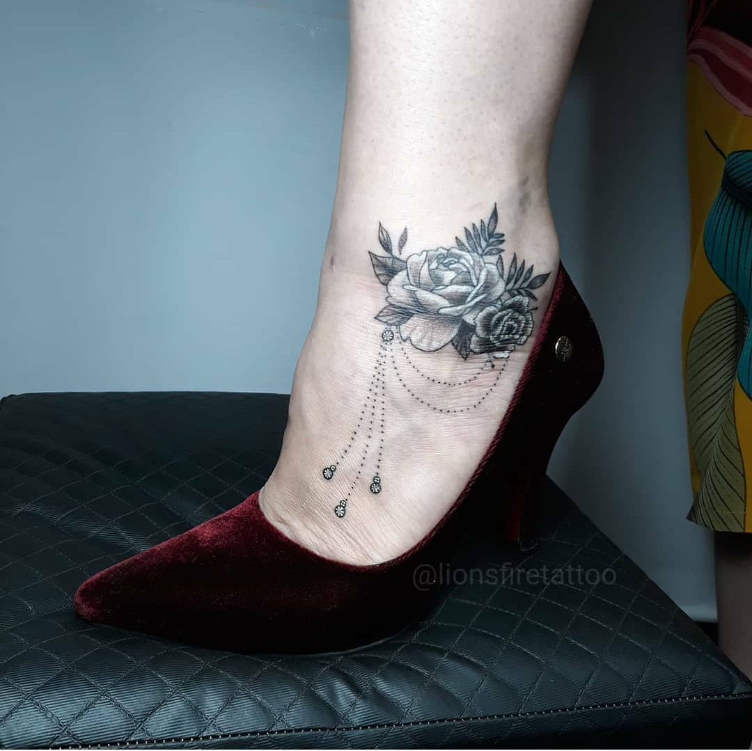 Imagem com tatuagem de flor no pé com correntes