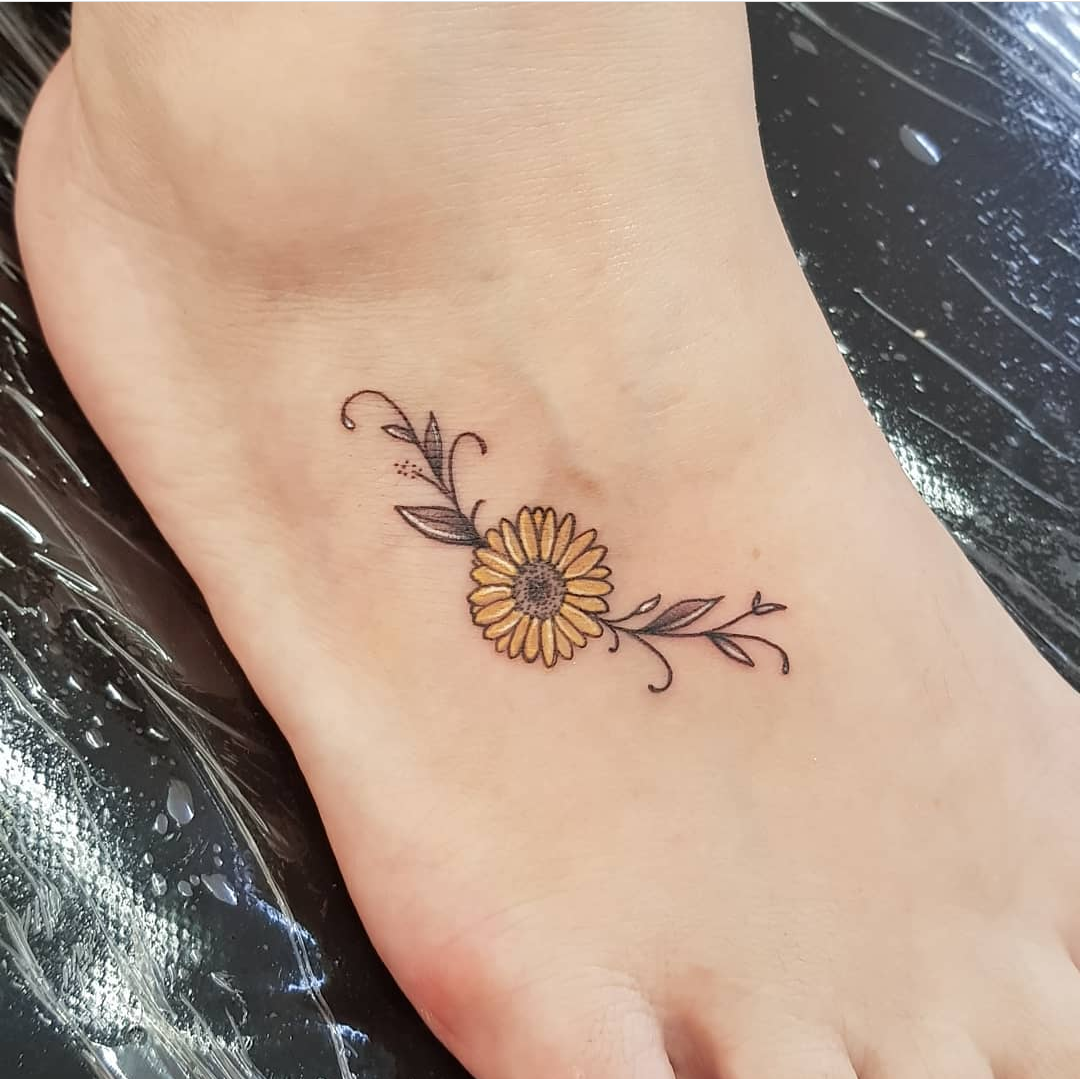 Imagem com tatuagem de flor no pé: girassol delicado