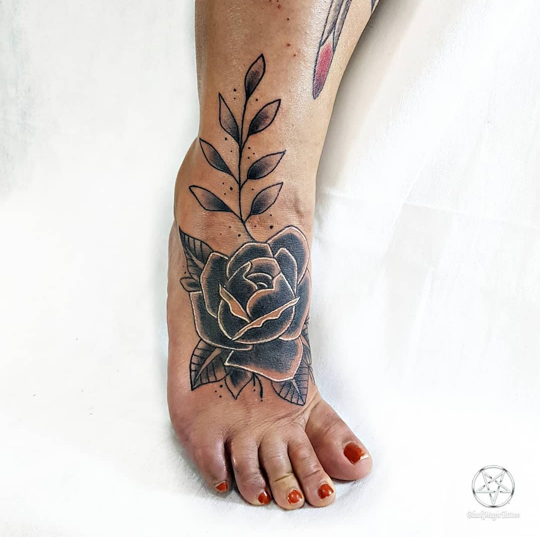 Imagem com tatuagem de flor no pé com detalhes em branco