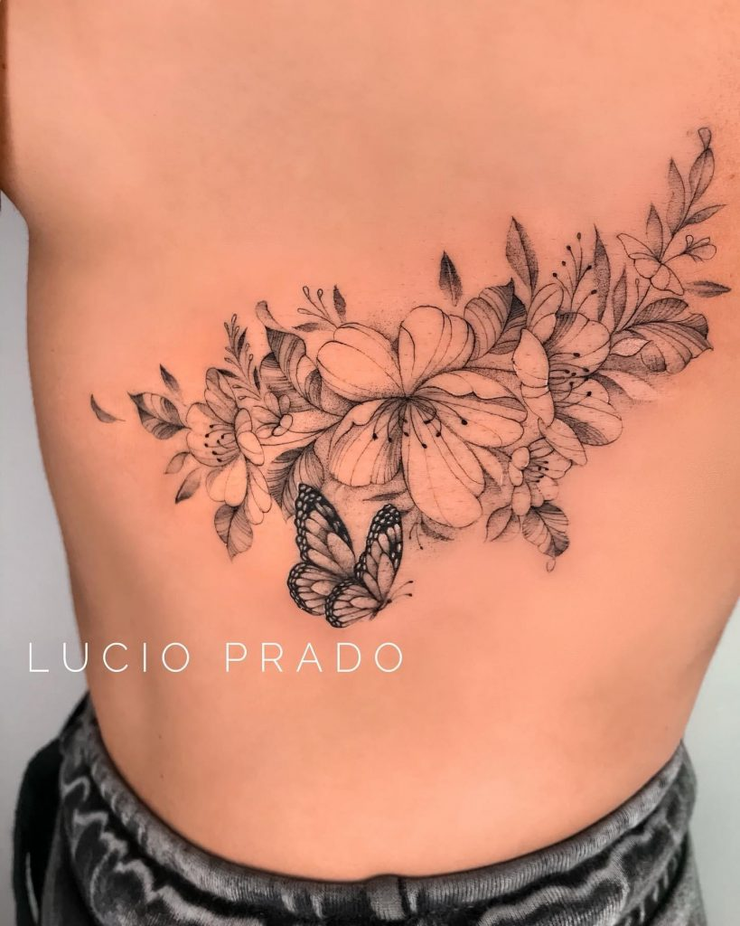 Imagem com tatuagem de ramo, flor e borboleta na costela