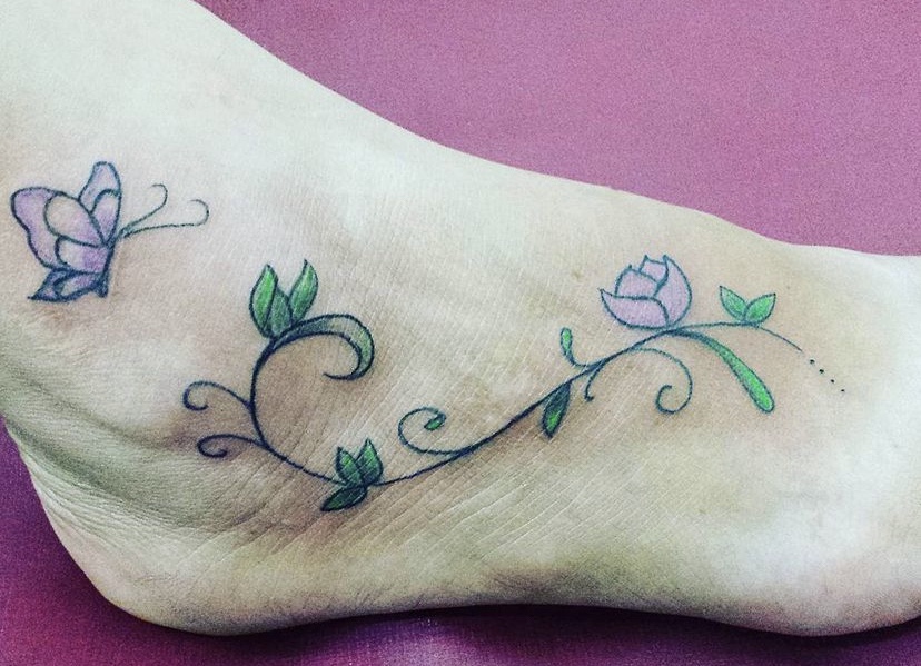 Imagem com tatuagem de flor no pé delicada colorida