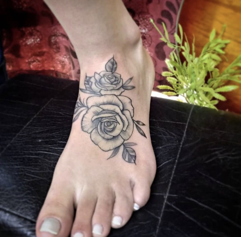 Imagem com tatuagem de flor no pé sombreada