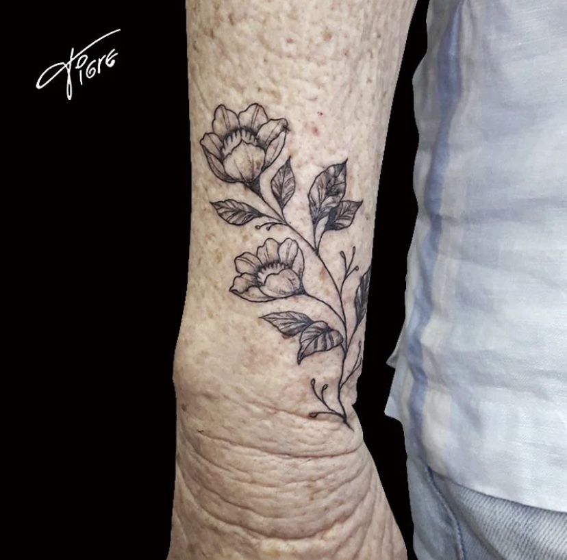 Imagem com tatuagem de ramo e flor no braço