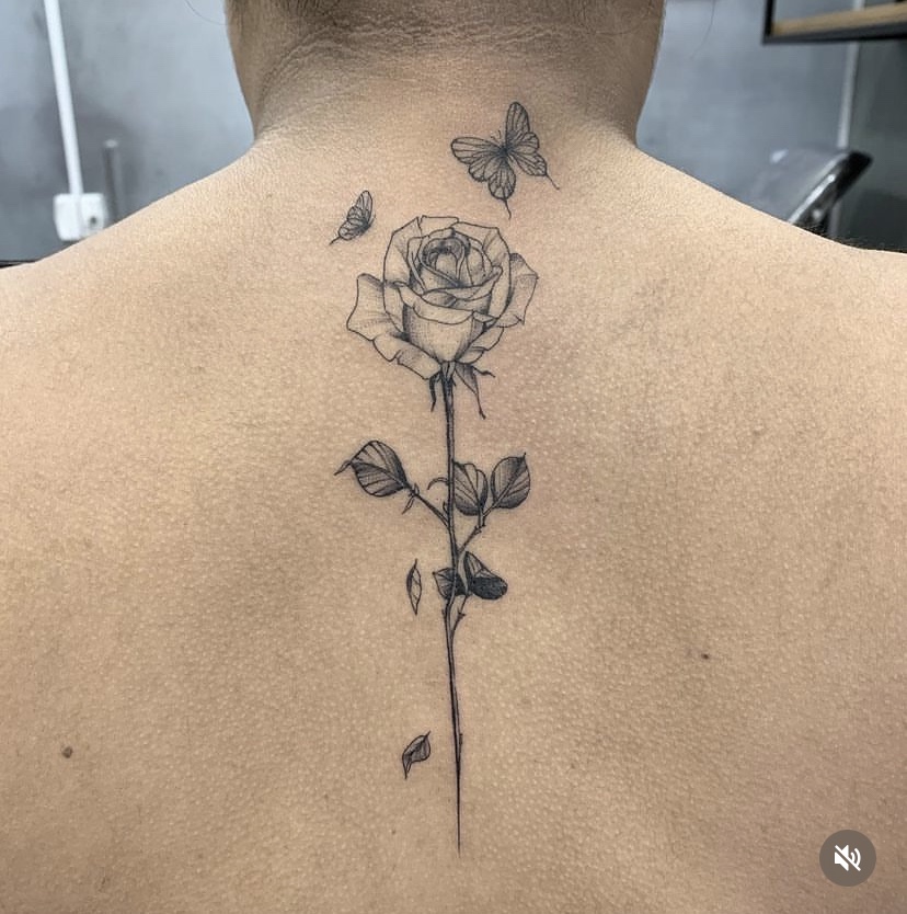 Imagem com tatuagem de flor nas costas: rosa e borboleta