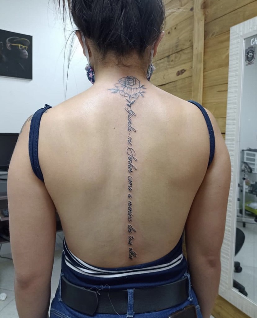 Imagem com tatuagem de flor nas costas e frase