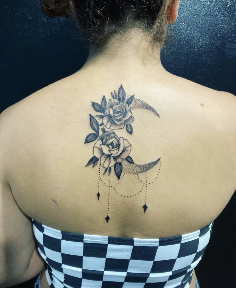 Imagem com tatuagem de flor nas costas em uma lua