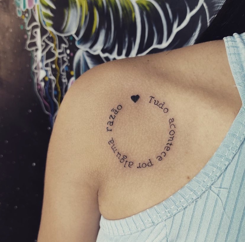 Imagem com tatuagem de frase circular no ombro