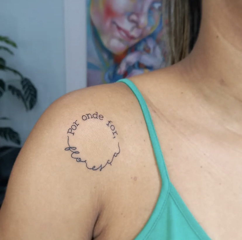 Imagem com Tatuagem de frases no ombro em círculo