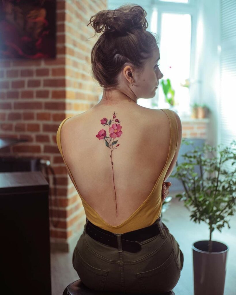 Imagem com tatuagem de flor nas costas: flores vermelhas