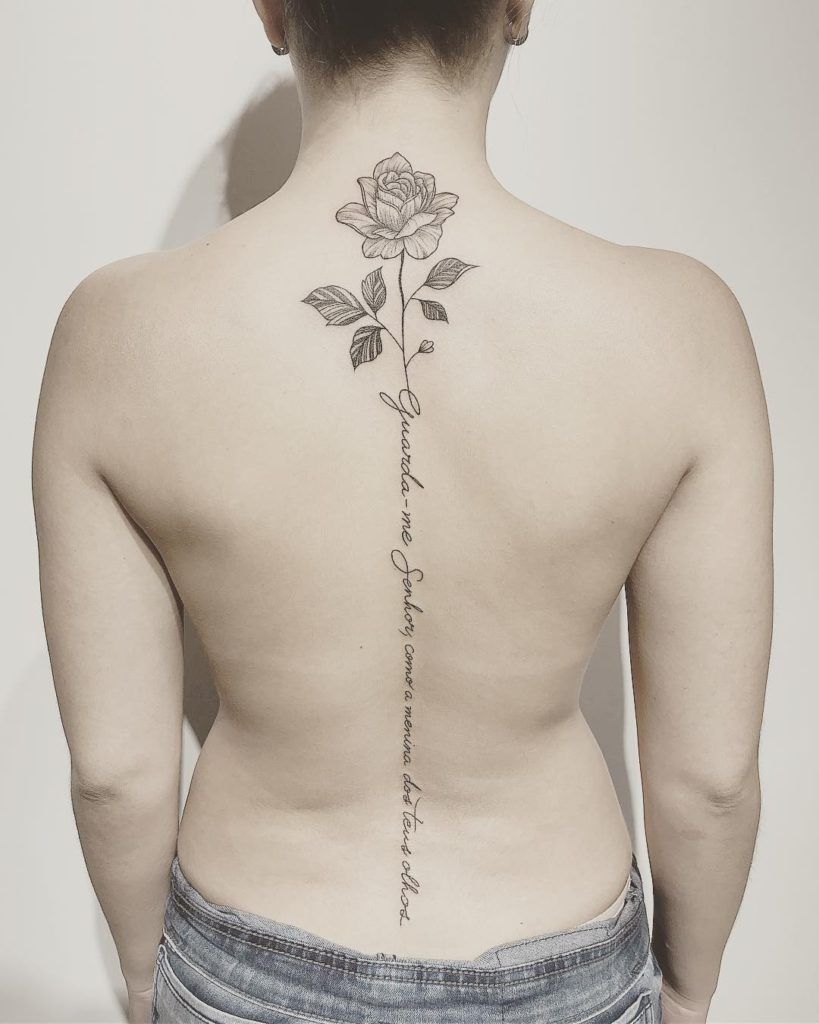 Imagem com tatuagem de flor nas costas com frase religiosa