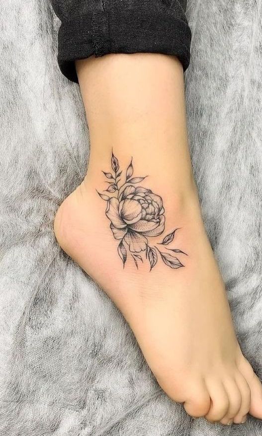 Imagem com tatuagem de flor no pé preta lateral