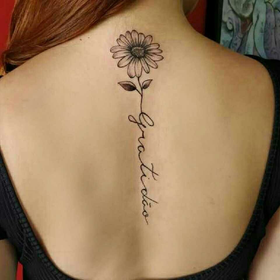 Imagem com tatuagem de flor nas costas: girassol e palavra "gratidão"