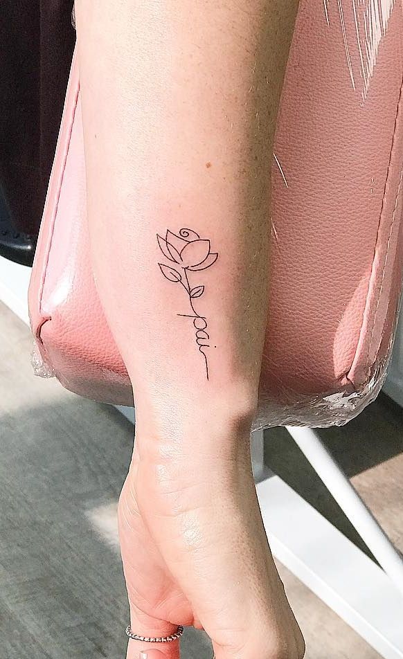 Imagem com tatuagem de ramo de flor com a escrita de "pai"
