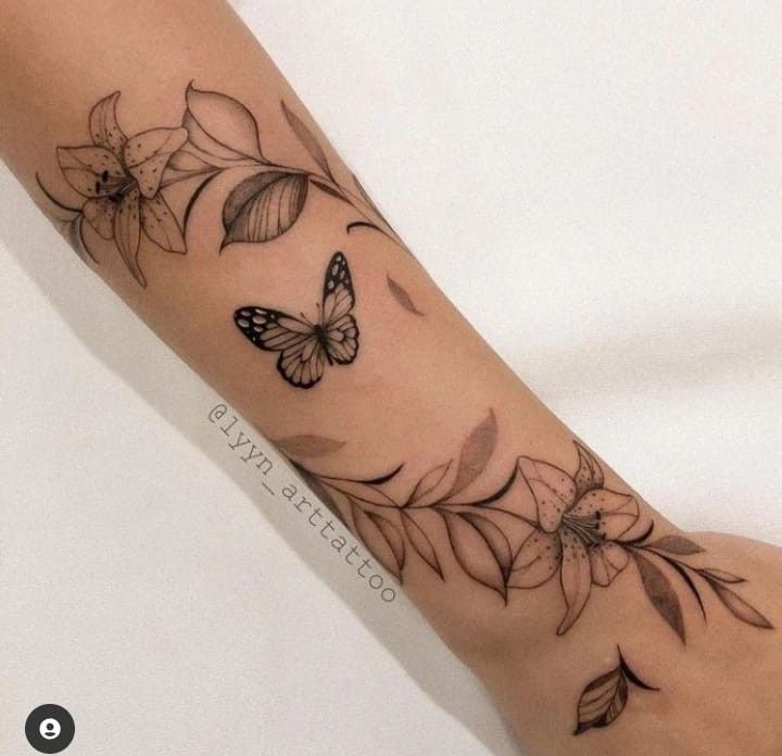 Imagem com tatuagem de ramo, flor e borboleta no braço